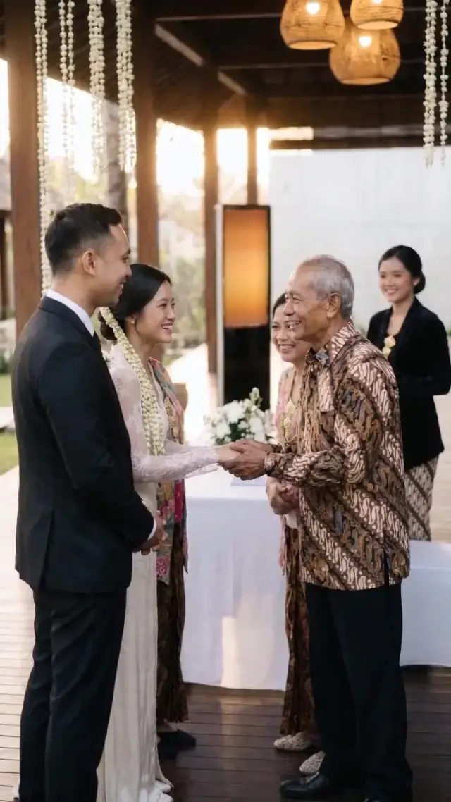 Pengantin menyambut tamu sepuh berbatik di paviliun kayu berhias ronce melati.